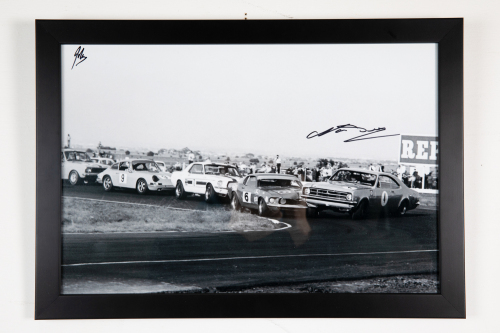 BEECHEY: A signed b/w photograph featuring Norm Beechey leading race circa late 1960s in HK Monaro, signed by Beechey, image 30cm high, 45cm wide