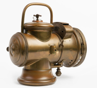 HEADLIGHT: A circa early 1900s Herm Riemann (Germany) brass headlight, convex lens width 18cm (7 inches), vertical bail handle, overall height 34cm [Location: Melbourne] - 2