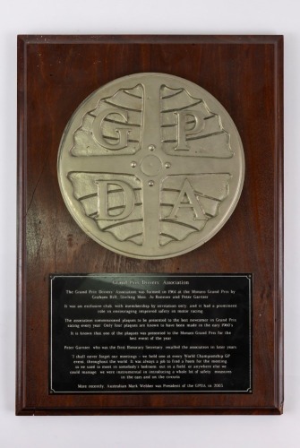 GPDA: A Grand Prix Drivers Association plaque, believed to be one of four produced in the 1960s, mounted on timber [Location: Perth]