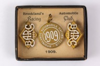 BROOKLANDS: A set of three 1909 Brooklands BARC membership lapel badges and medallion [Location: Perth]