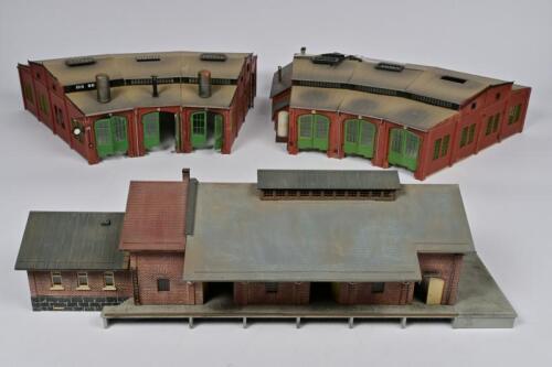 TRACK SIDE BUILDINGS: Three track side buildings including station by Kibri, and two engine sheds by Vollmer, some parts detached and lacking