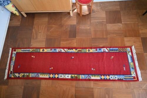 RUGS: A handwoven Aztec style red ground runner with a geometric border, 298 x 78cm
