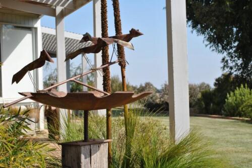 DARREN GILBERT, An iron bird bath on timber stand with iron footplate and surmounted with sculptural birds on a branch, 136cm high, 195cm wide *(see note)