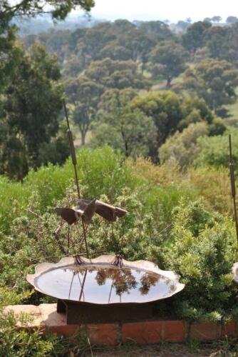 DARREN GILBERT , An iron bird bath with sculptural birds on the surrounding rim, 30cm high, 54cm diameter *(see note)