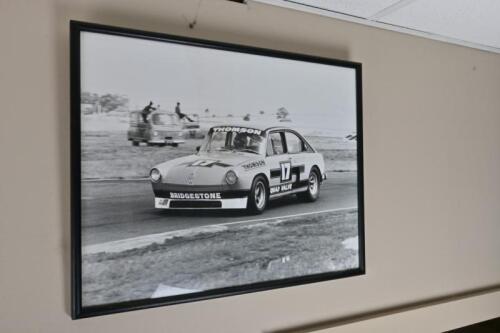 VW V8: A framed period photograph of Brian Thomson at the wheel of his VW V8 leading Bob Jane at Calder, signed & inscribed on rear
