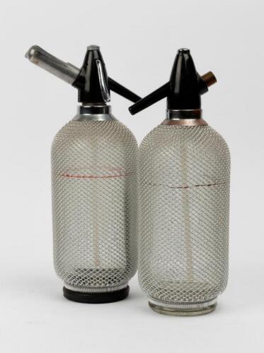 SODA SIPHONS: A pair of vintage mesh mounted glass soda siphons, 35cm high