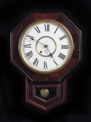 CLOCK: An antique 8-day octagonal wall clock by New Haven USA, 60cm high x 43cm wide, with pendulum