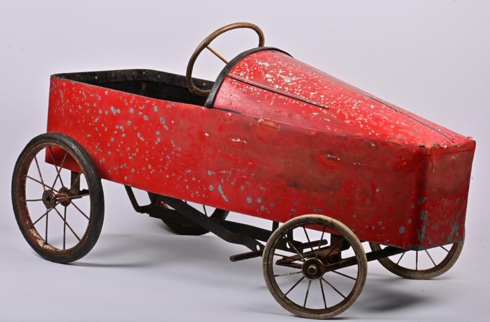 PEDAL CAR: A postwar childrens red metal pedal car, 49cm high x 91cm