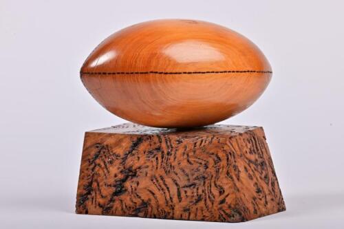 RUGBY: A carved hardwood rugby trophy on burrwood stand, 18cm high
