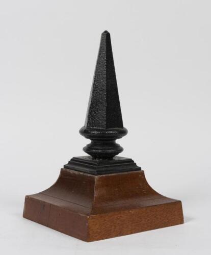 FINIAL: A cast iron finial mounted on oak stand, 30cm high