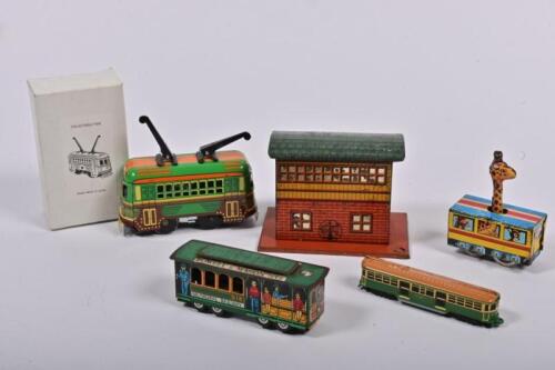 TRAMS: A collection of toy trams and a tin building, including lithograph printed toys