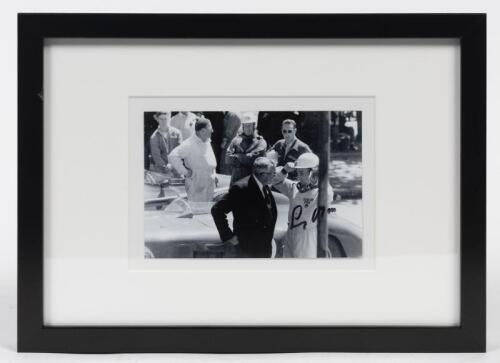 STIRLING MOSS: A small signed photograph of Stirling on the starting grid at Albert Park with a 300S and 250F Maserati behind him, mounted and framed.