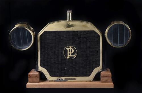 PANHARD AND LEVASSOR/RUSHMORE: A Panhard & Levassor radiator from a 1911 Panhard & Levassor Berline Type X5 and a pair of Rushmore headlights on stand