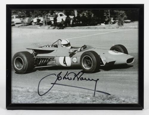 HARVEY: A signed photograph of John Harvey at the wheel of his 2.5 litre Repco-Brabham circa 1970, signed by Harvey in black ink, framed and glazed, image 14cm high x 19cm wide.