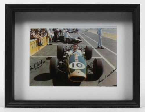BRABHAM: A signed photograph of Sir Jack and Denni Hulme in pit straight, likely during the mid-60s Tasman Series, signed by Sir Jack and Ron Tauranac in black ink, mounted and box framed, image 20cm high x 29cm wide.