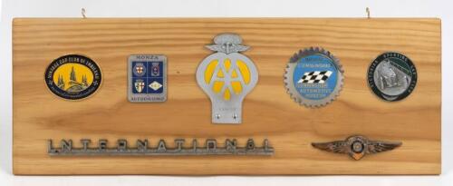 GRILLE BADGES: A collection of car grille badges mounted on a pine backboard, including an enamelled Victorian Sporting Car Club badge, a Briggs Cunningham Automotive Badge and a 1960-61 AA membership badge, the board 24 x 66cm