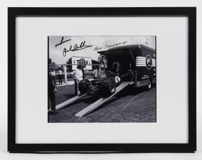 BRABHAM: A duel signed photograph of the Repco Brabham V8 being unloaded the Repco Brabham truck, signed by Brabham and Tauruanac in black ink.