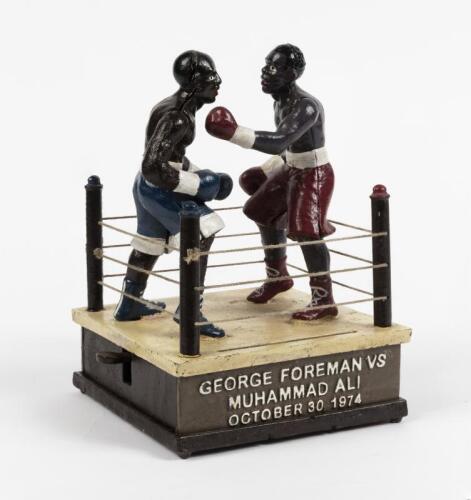 MUHAMMAD ALI: A cast iron moneybox commemorating the Rumble in the Jungle between Muhammad Ali and George Foreman, 1974, with mechanical operated arms, 21cm high