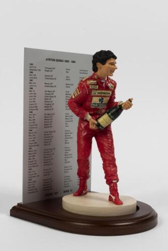 AYRTON SENNA: A 1:9 scale limited edition (2194/7500) cold cast porcelain resin figure of Ayrton Senna sculpted by Paul Szeiler for Endurance Ltd, on wooden base with engraved plaque, NIB and accompanied by a COA from The Art of Sport, 22cm high