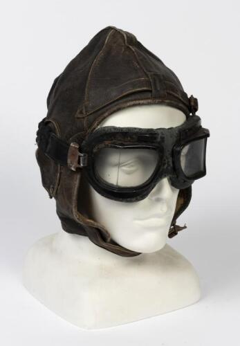 WWII FLYING HELMET AND GOGGLES: An Australian made WWI brown leather flying helmet with headphones and a pair of goggles, bears embroidered label to the interior 'Stagg Gloves'. Stagg helmets are thought to have been worn by RAAF aircrew in Malaya circa 1