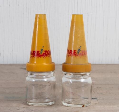 FIREZONE: Two small glass oil bottles with Firezone plastic oil pourers, 14cm high and 4.5cm diameter, both with cracks to pourers