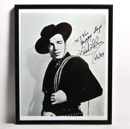 LASH LA RUE: A black and white framed portrait of Lash La Rue with his whip over his shoulder, personally inscribed and signed by Lash La Rue. 19.5cm wide, 25cm high.