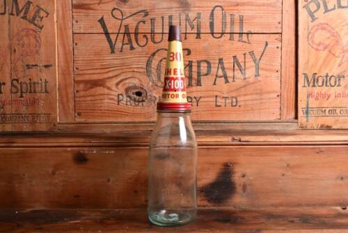 SHELL: A circa 1960s "Shell" embossed one imperial pint oil bottle, with a 1950/60s "Shell X-100 Motor Oil" tin pourer and dust cover