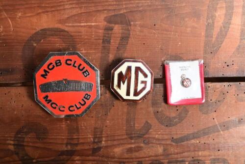 MG: Three MG car badges and pendant. 'MGB CLUB/MGC CLUB' membership badge & small 'MG' necklace pendant