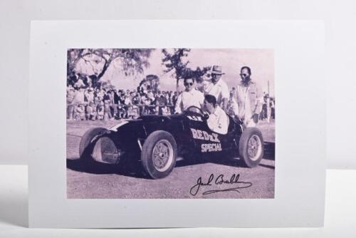BRABHAM: A black and white picture of Sir Jack Brabham in a Cooper T23 Bristol at Mount Druitt. Sir Jack Brabham signature