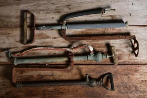 DRUM PUMPS: Three early drum hand pumps, two with foot hold plates, the other in brass, largest 71cm high